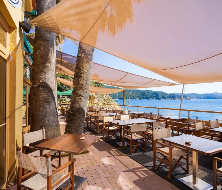 Terrazza ombreggiata dell’Osteria di Mare con tavoli affacciati sul mare
