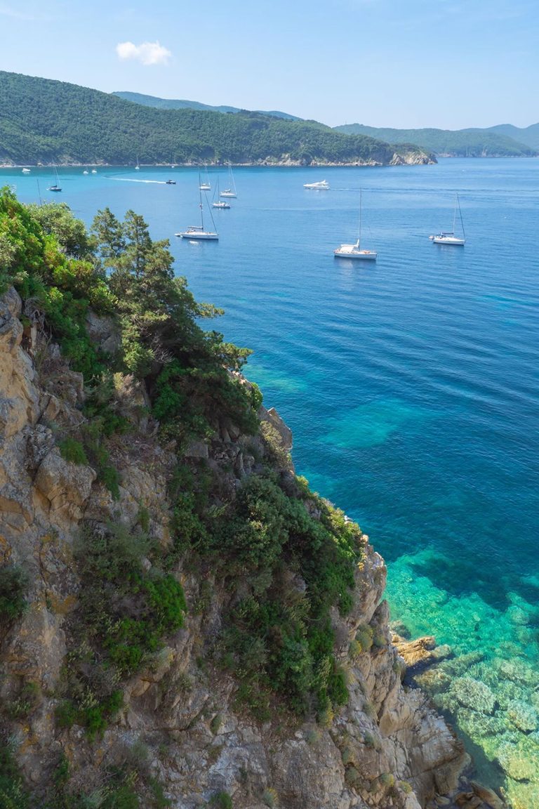 Scogliera dell’Enfola con mare cristallino e barche a vela all’ancora, Isola d’Elba