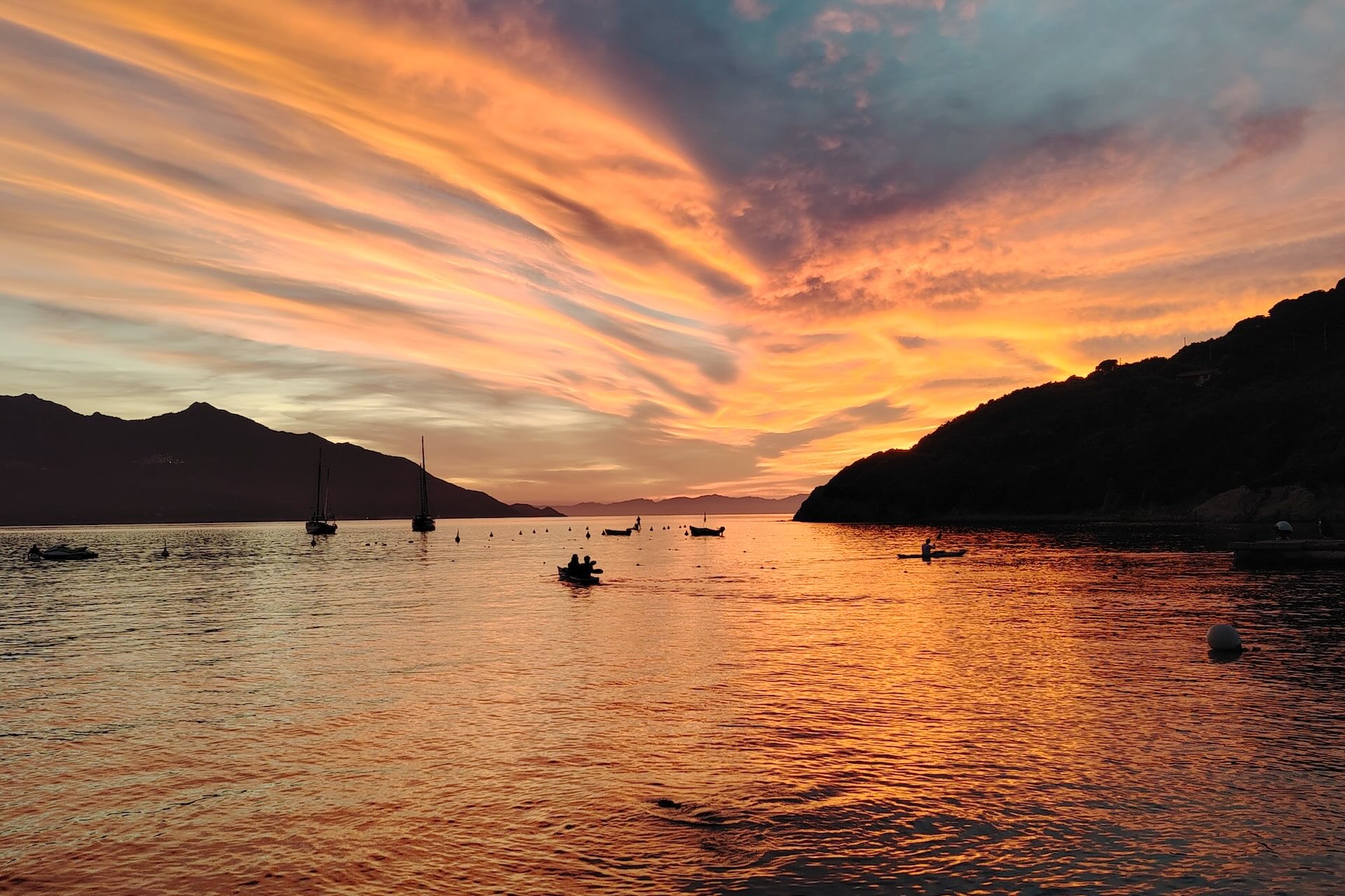 Kayak al tramonto in una baia tranquilla, riflessi dorati sull’acqua e profilo delle colline