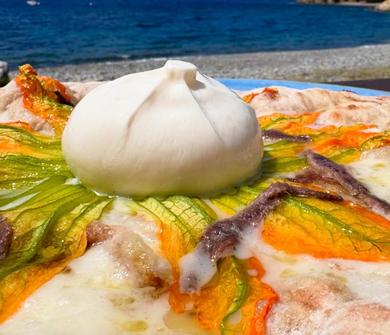 Pizza gourmet con burrata, fiori di zucca e alici servita sul mare a Enfola