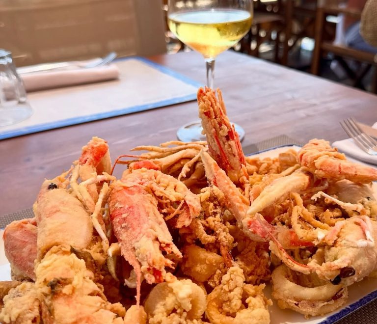 Frittura di pesce con scampi e calamari servita all’Osteria di Mare con calice di vino bianco