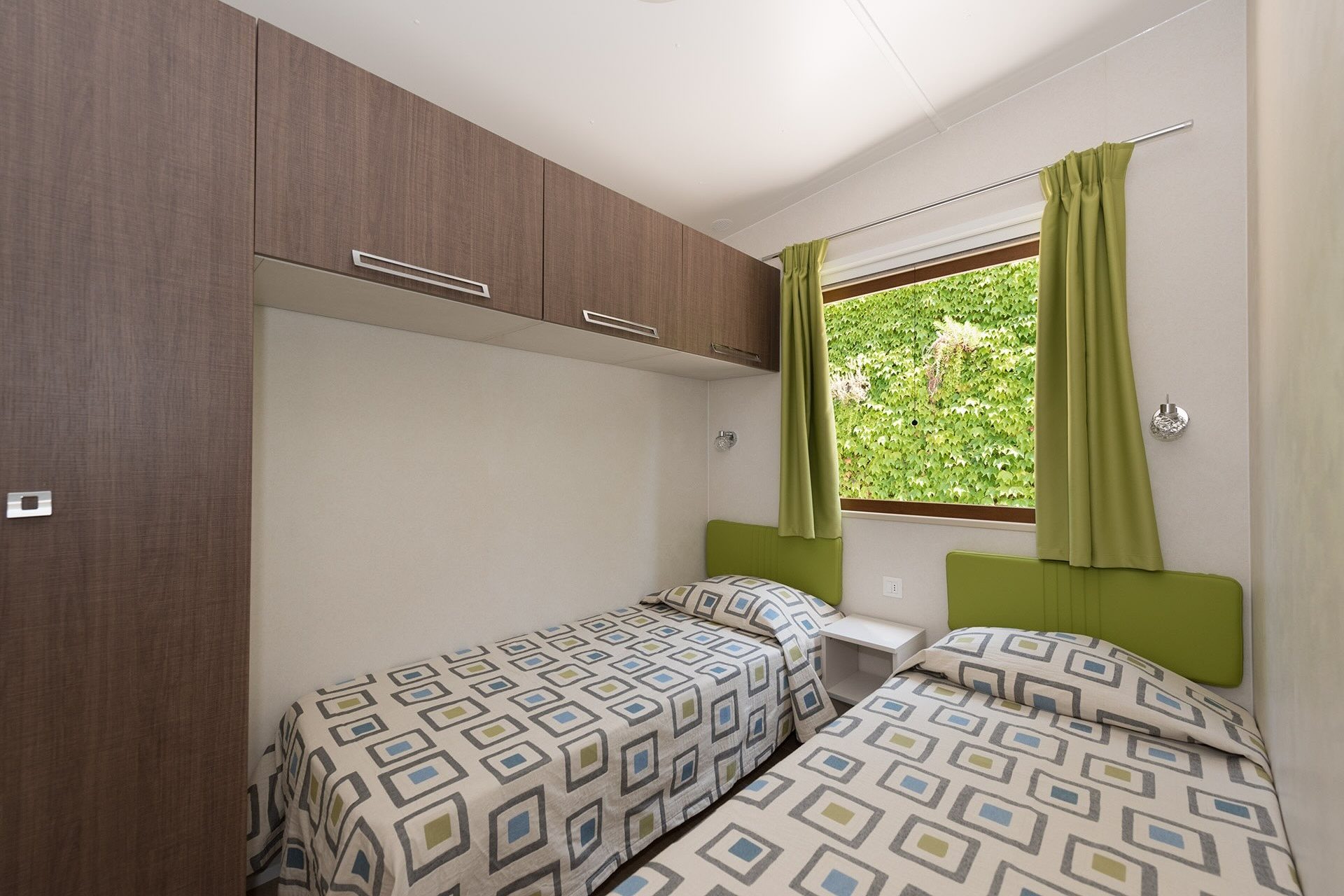 Camera con letti singoli e armadio in chalet del campeggio