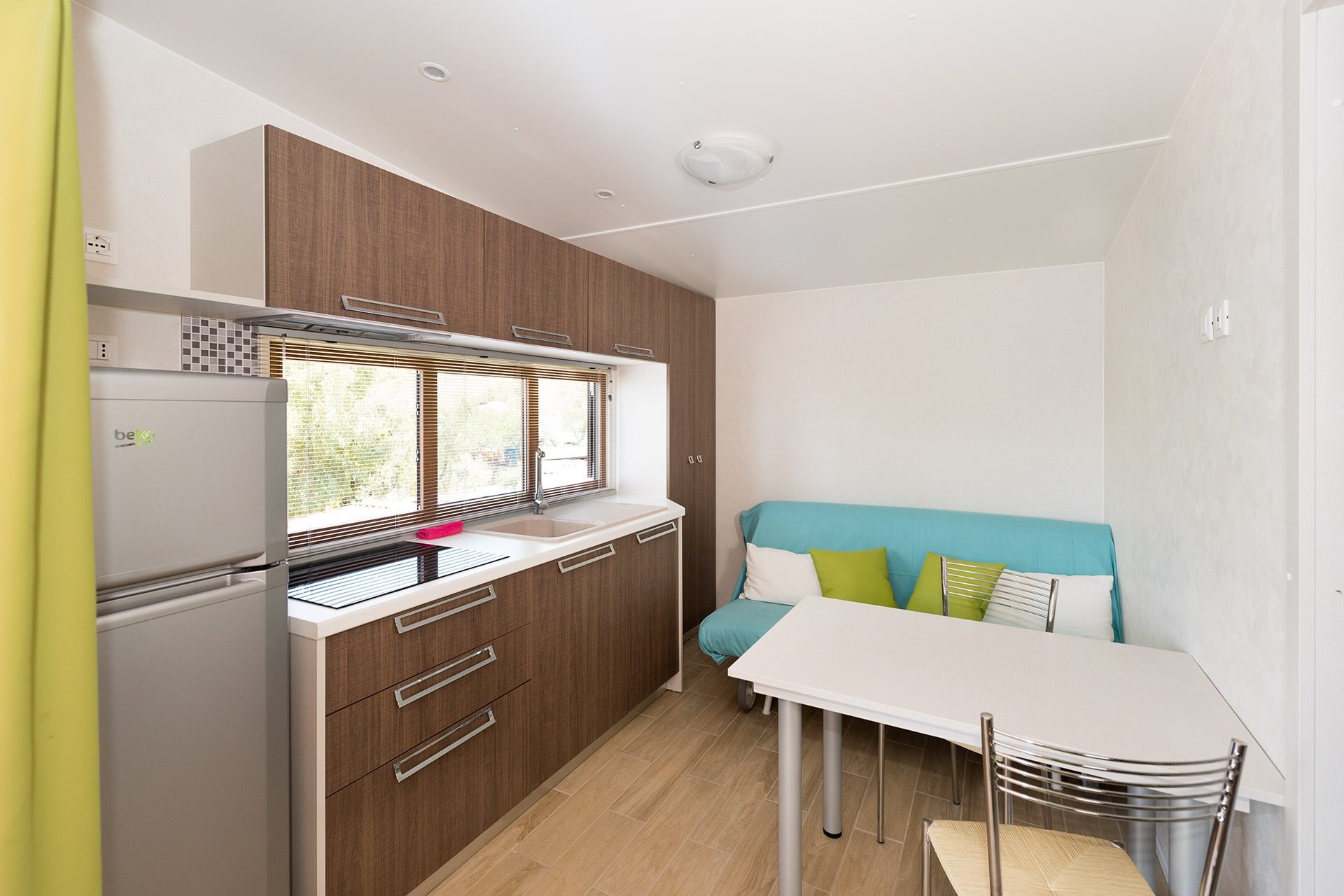 Zona giorno con tavolo e cucina in chalet del Camping Enfola