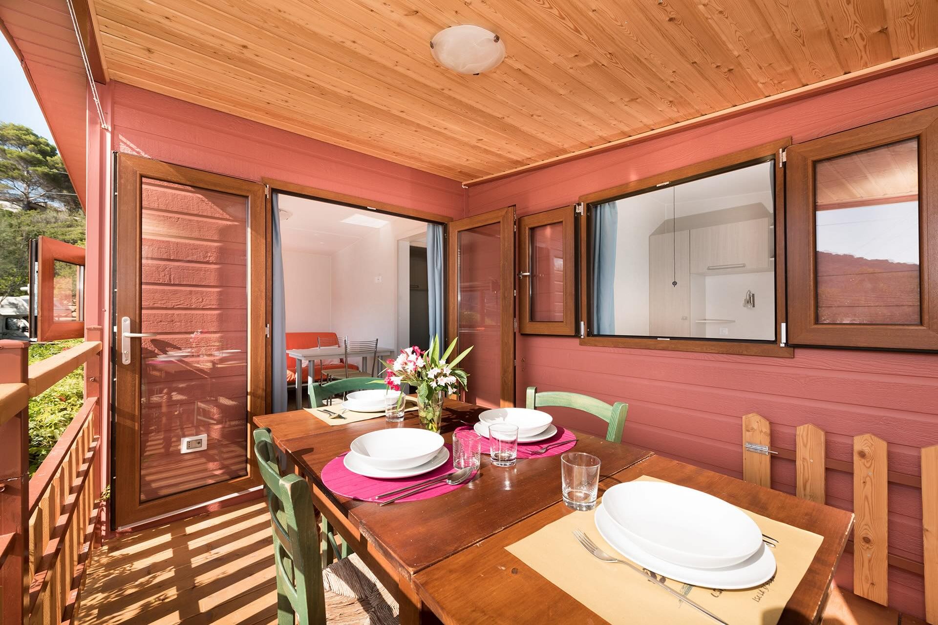 Veranda coperta con tavolo davanti a uno chalet immerso nel verde