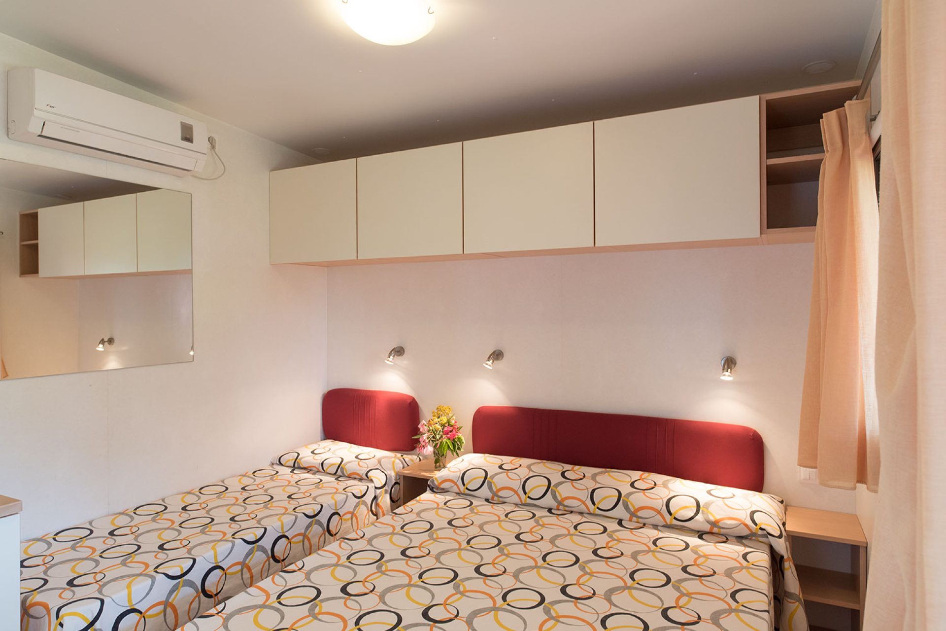 Camera con letto matrimoniale e singolo all’interno di un bungalow del campeggio