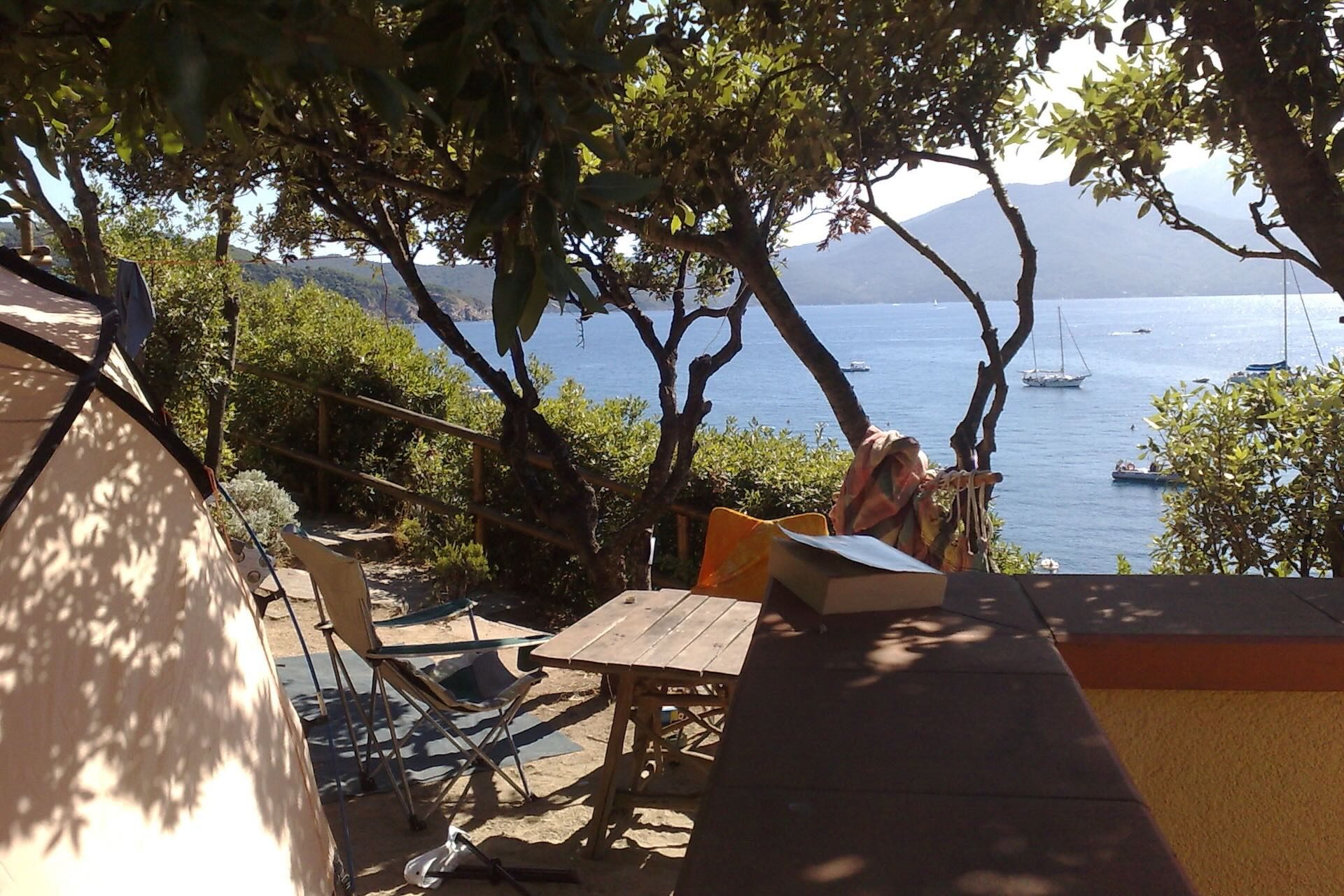 Piazzola panoramica del Camping Enfola con tenda e terrazza vista mare tra gli alberi